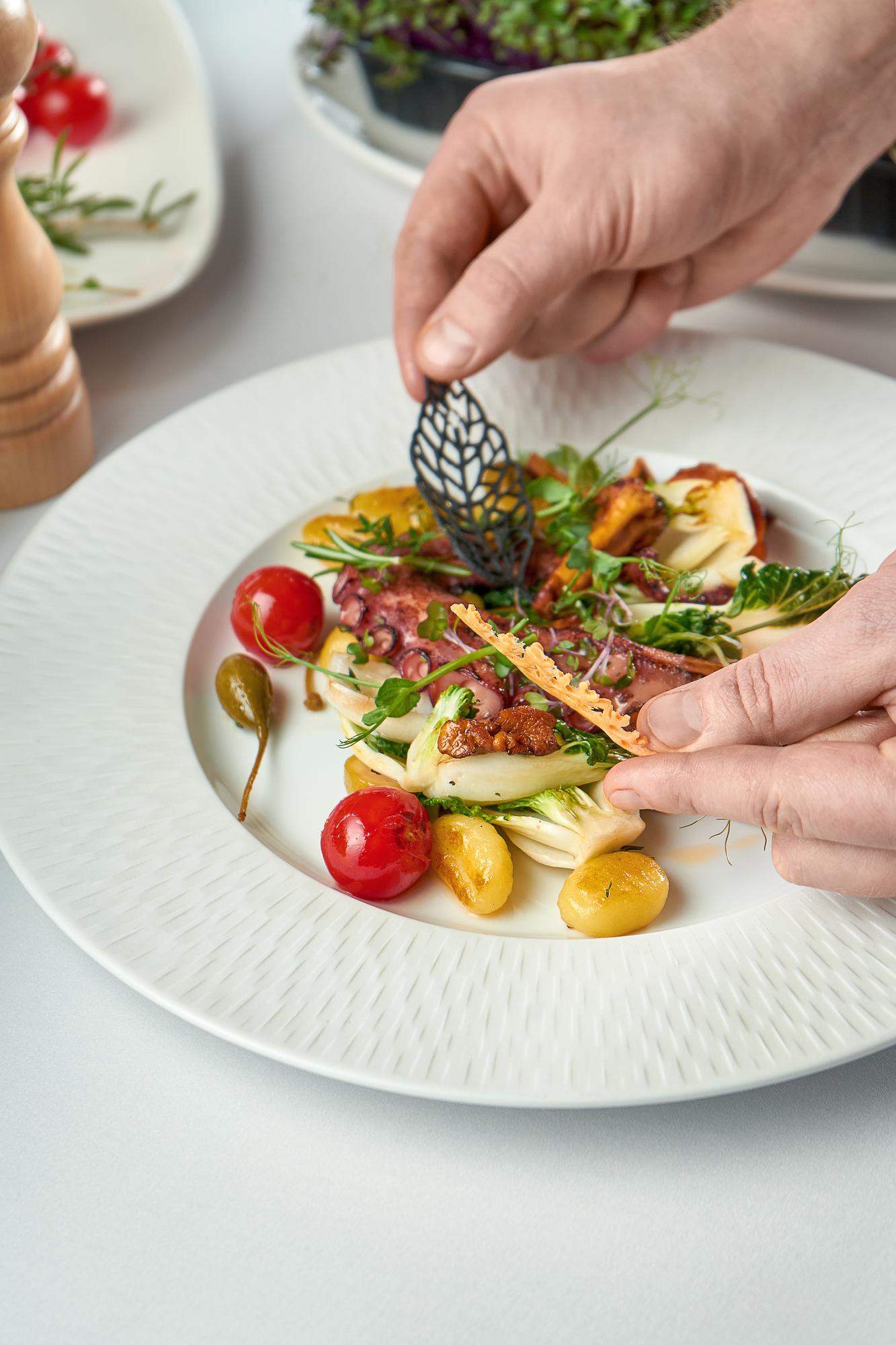 Chef arranging plated seasonal dish on wooden table